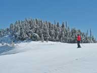 Mary skiing across top of Superstar on her way to Skye Lark under a beautiful bright blue sky.