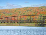 Fall Foliage colorfully silhouettes bridge across Snow Shed pond at Killington.