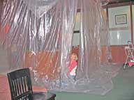 Mary placing plastic sheeting around the bar in the Great Room.